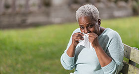 woman sitting on park bench with allergies