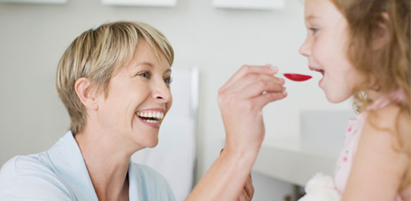 Mother giving daughter spoonful of medicine