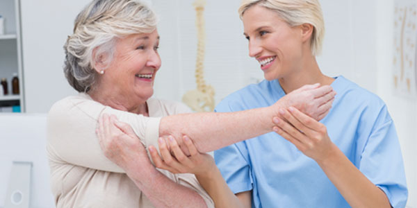 Elderly woman being assisted by nurse with arm stretching exercises
