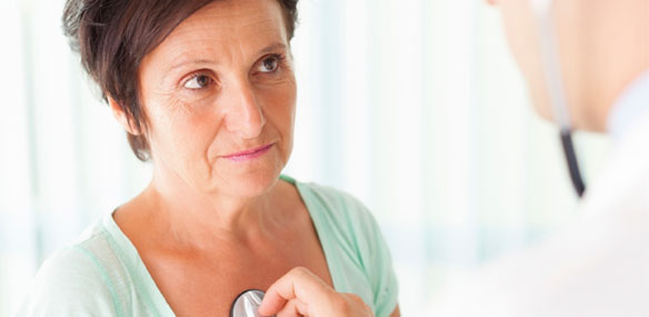 Doctor listening to heart of middle-aged woman