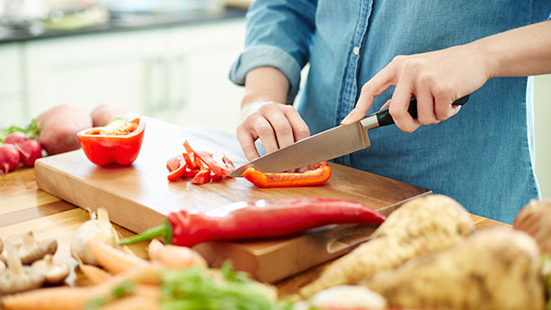 Close up of woman cutting vegetables in kitchen