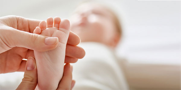 Doctor examining foot of newborn baby in hospital