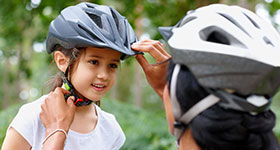 Mom adjusting girl's bike helmet