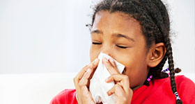 Girl blowing nose into tissue