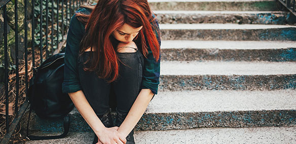 Teen girl sitting on steps with head down
