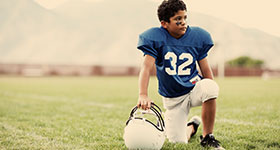 youth football player kneeling on field