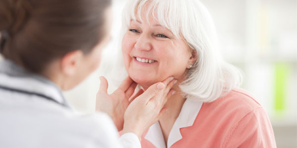 Doctor examining senior woman's neck
