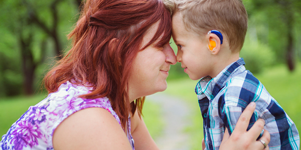 Mother and son wearing a hearing aid in a park