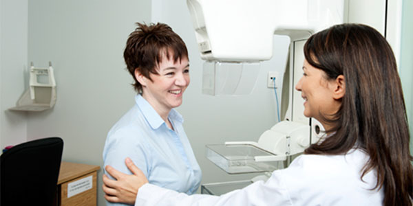 Imaging technician assisting mammogram patient