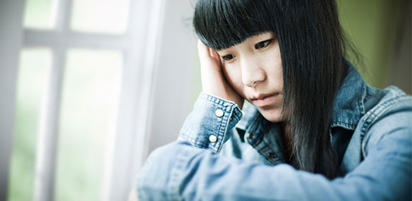 Sad Asian teen female looking out window