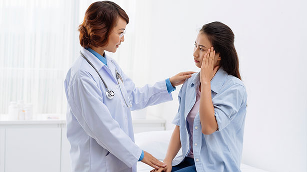 Asian doctor and female patient with headache