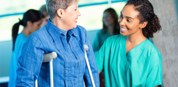 Mature woman on crutches with attendant