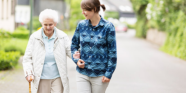 Elderly woman and caregiver walking