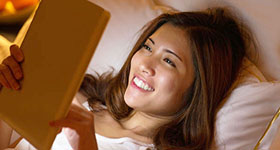 Asian woman with mobile device in bed