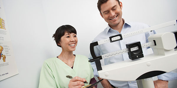 Nurse checking male patient's weight on scale