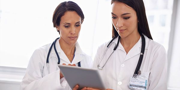 Two female doctors looking at digital tablet research