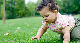 Baby girl crawling in grass