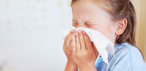 Little girl sneezing into tissue