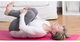 Middle-aged woman laying down on yoga mat stretching back