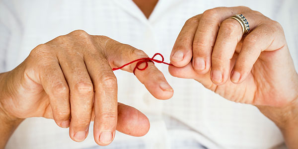 Hand with red string tied around finger