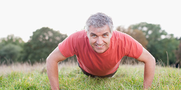 Older man doing push ups outside on the grass