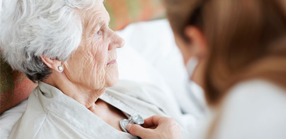 Doctor listening to elderly woman's heartbeat