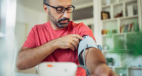 Middle-aged man checks blood pressure with cuff at home