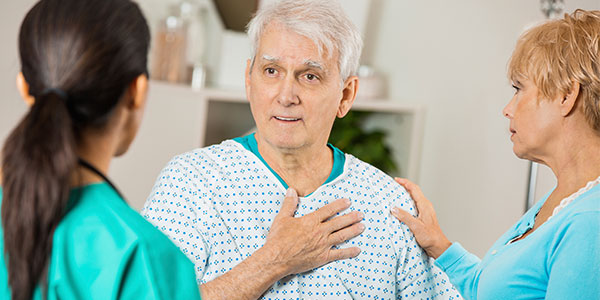 Elderly man explaining heart symptoms to nurse