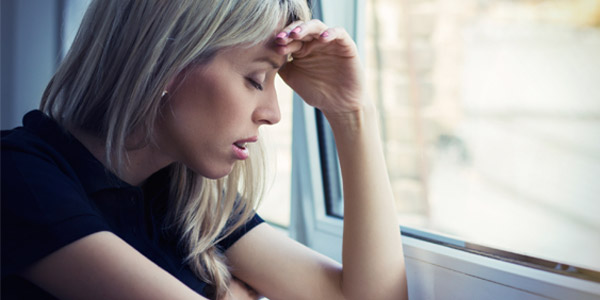 Depressed young woman looking out window