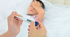Mom taking temperature of asian boy with fever