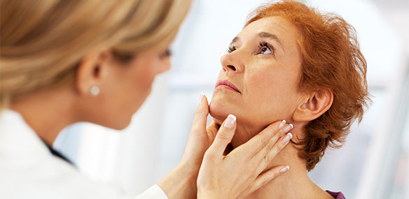 Doctor examining female patient's throat glands