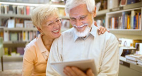 Caucasian senior couple looking at digital tablet in library