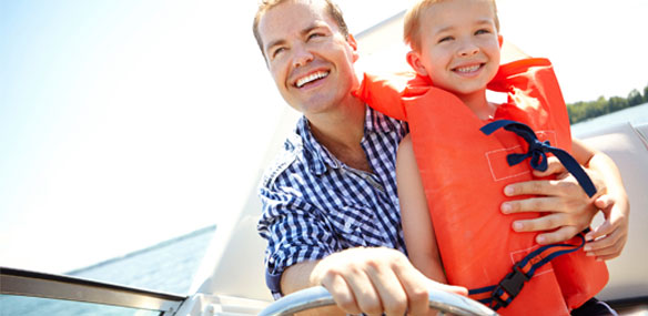 Boy with life vest in boat with Dad