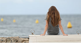 Teen girl sitting on end of dock