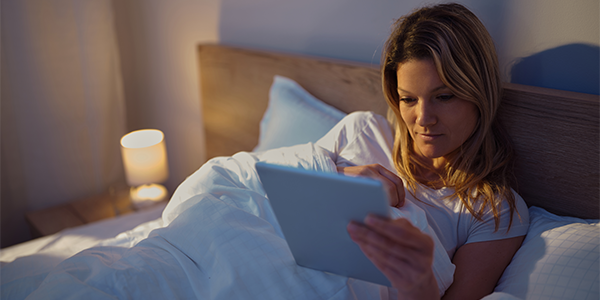 Young Hispanic woman view mobile device in bed