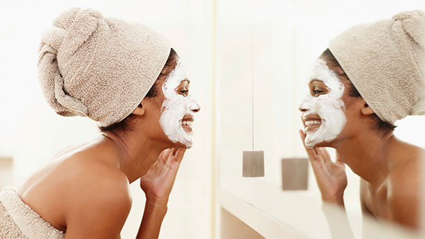 African American woman washing her face looking in the mirror