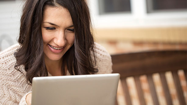 Woman smiling while reading on tablet